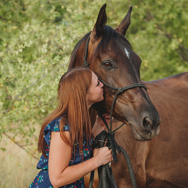 Girl kissing a bay horse.