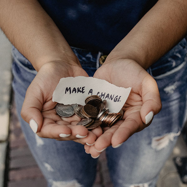 Person holding coins with a note that says make a change.