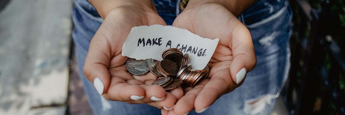 Person holding coins with a note that says make a change.